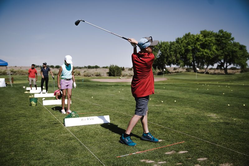 A golf coach working with a group of students along the practice ground