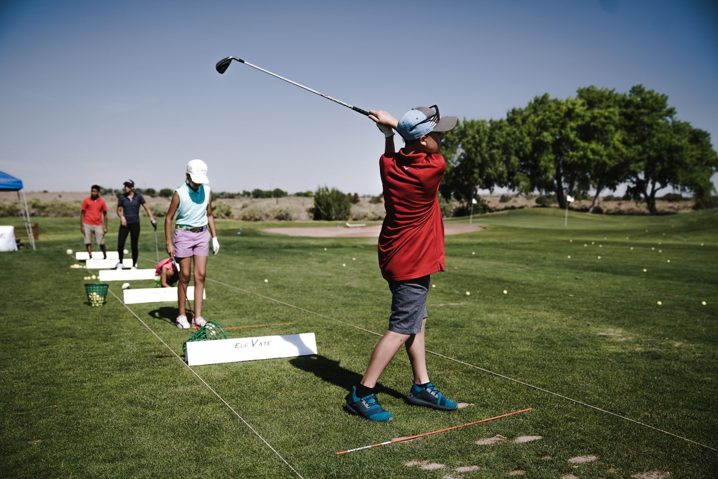 A golf coach working with a group of students along the practice ground