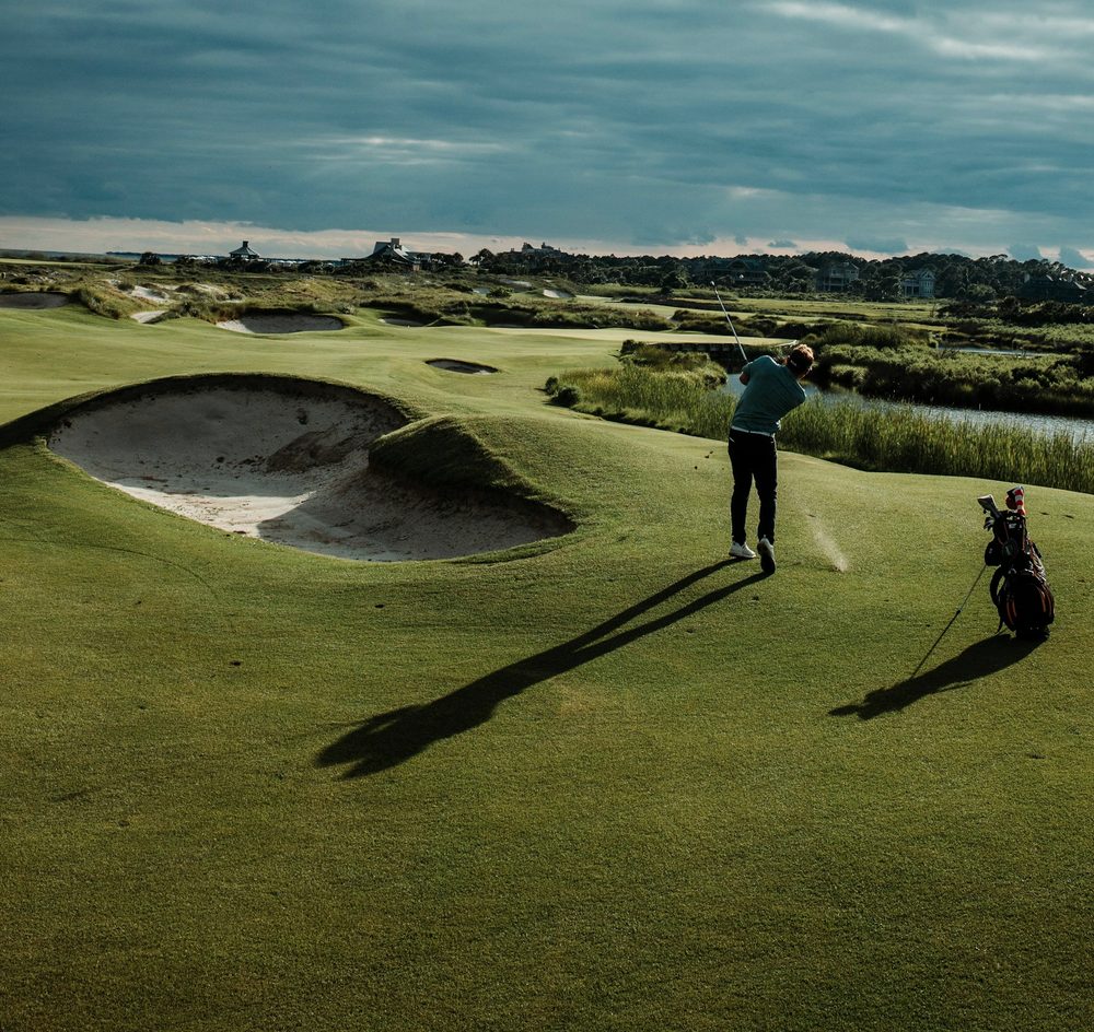 A golfer playing from beside a bunker on a links course